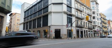 Un edificio moderno con entrada en esquina, ventanas grandes y escaparate visible.