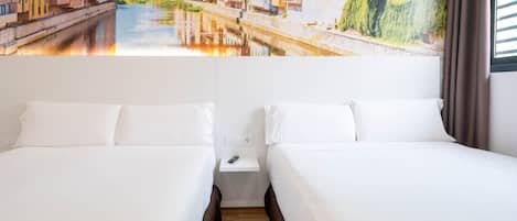 Habitación de hotel con dos camas, una mesita de noche y un mural de un paisaje urbano.