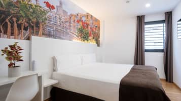 Habitación de hotel con cama, escritorio, silla, planta en maceta y un cuadro de un paisaje urbano.
