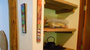 Un couloir étroit avec des étagères en bois, un panier et un récipient en plastique.