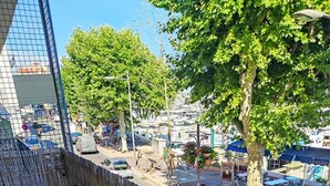 Un balcon donnant sur une rue, une clôture en bois et des sièges d’extérieur.