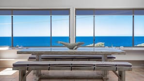 A room with a large window overlooking the sea, a wooden bench, and a whale sculpture on the windowsill. - Noah's 46 Cliff Road (Forster)