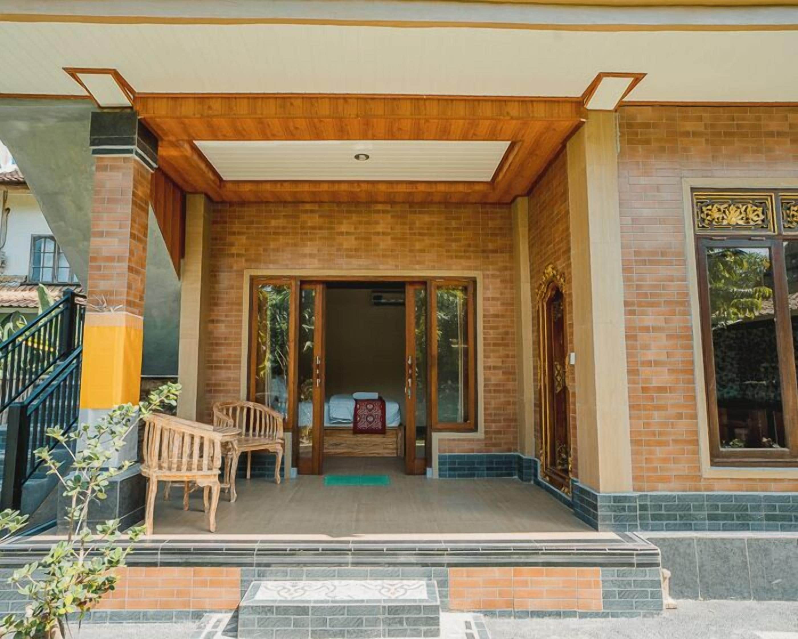 A hotel entrance with a covered porch, a wooden bench, and a set of double doors leading inside.