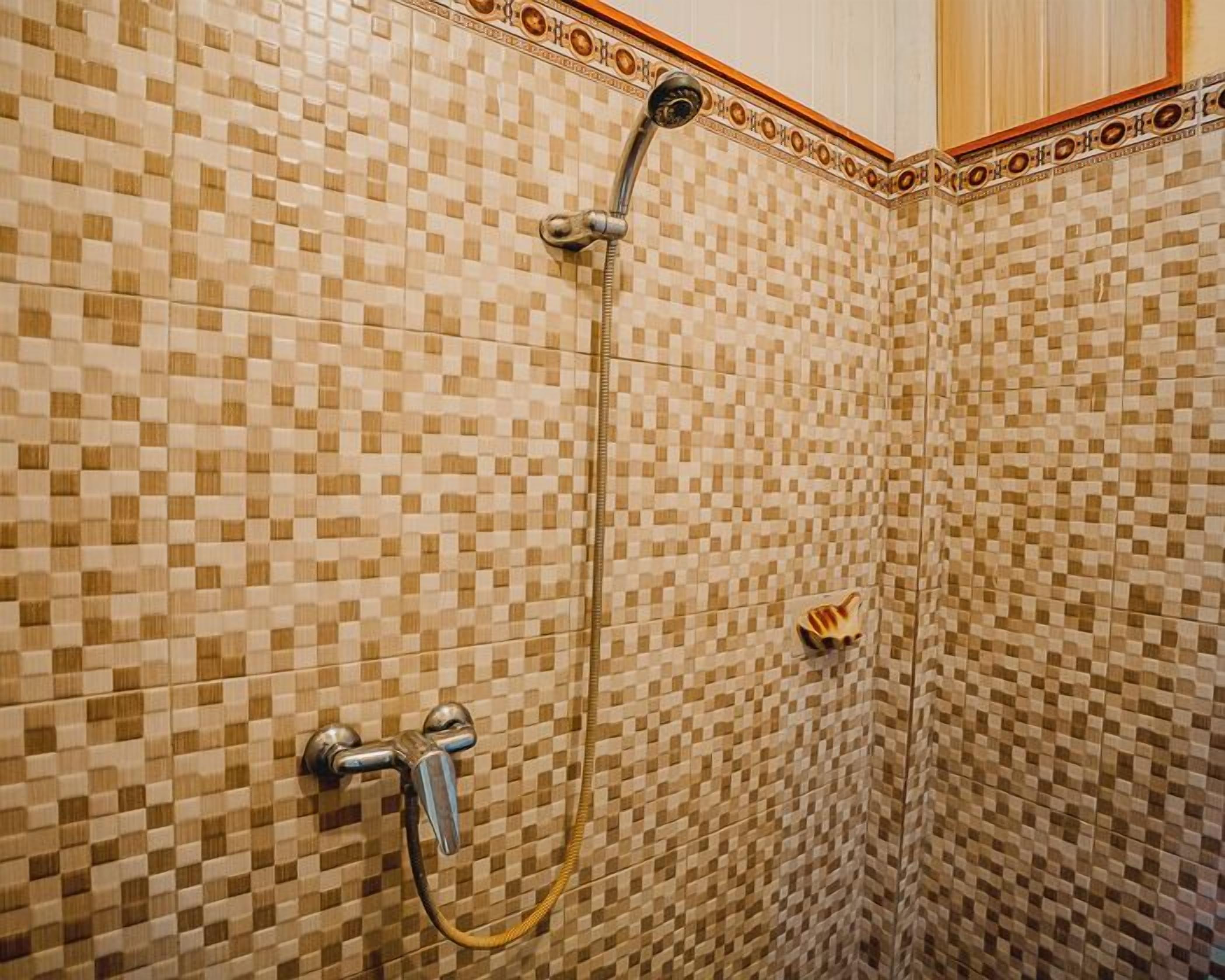 A shower with a checkered tile pattern and a metal showerhead.