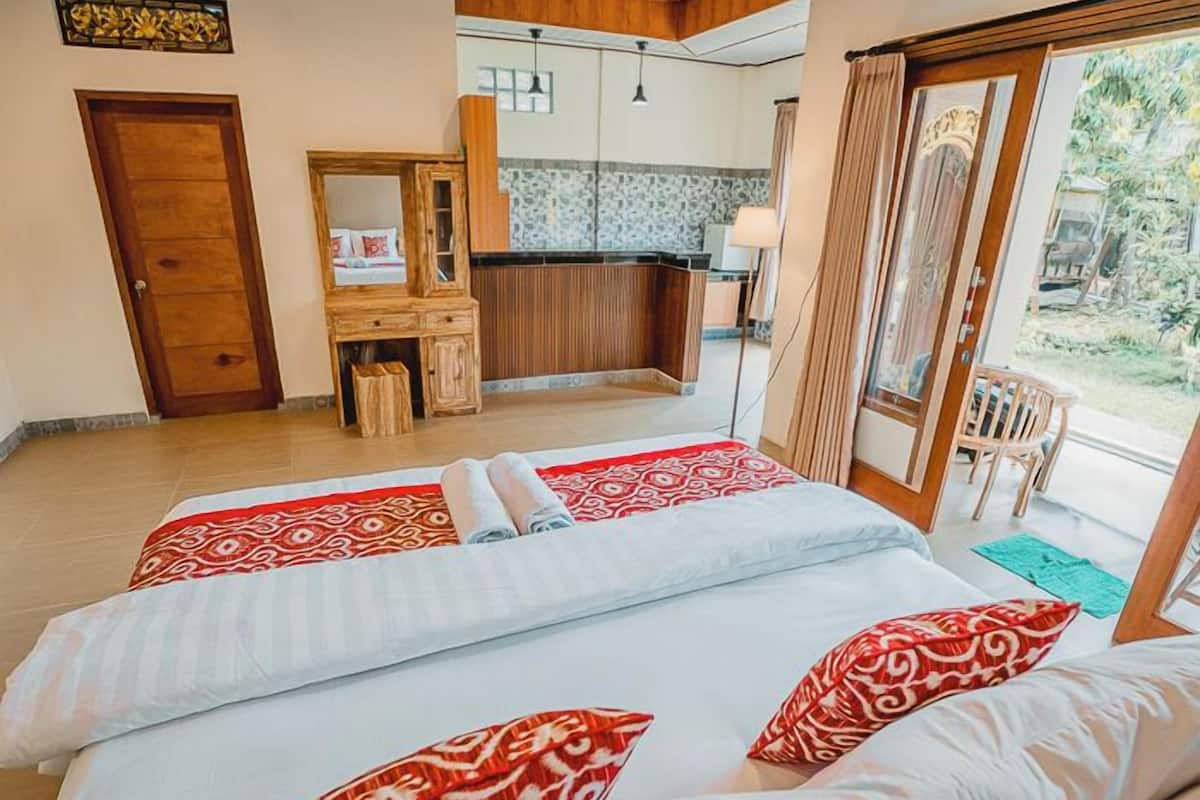 A hotel room with two beds, a wooden desk, a bathroom, and a view of the outdoors.