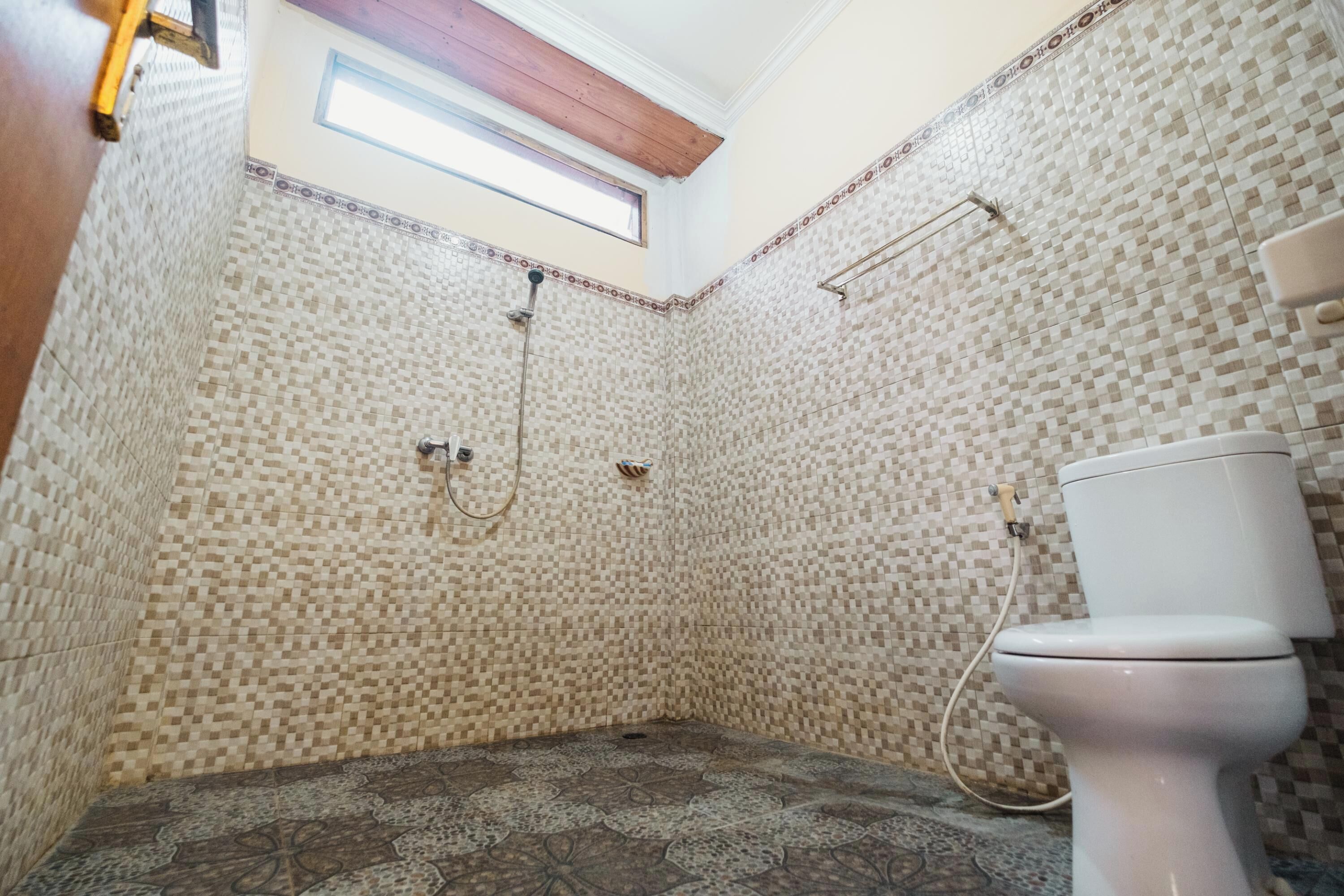 Een badkamer met mozaïektegels, een dakraam, een douche en een toilet.