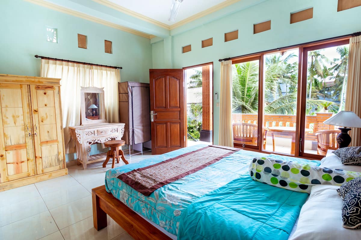 A bedroom with a bed, a desk, a wardrobe, and a view of the outside.