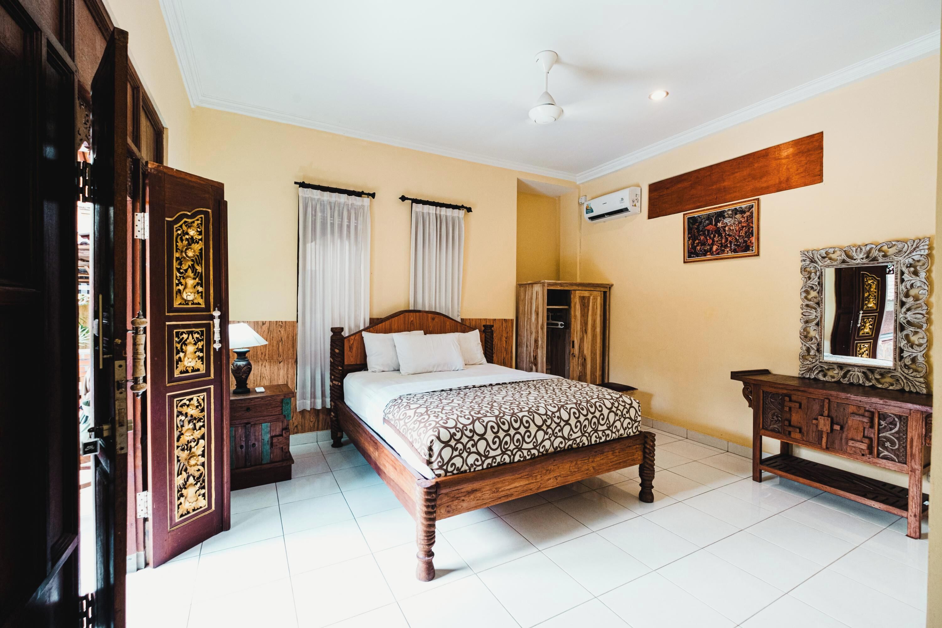 A bedroom with a wooden bed, a nightstand, a wardrobe, and a mirror on the wall.