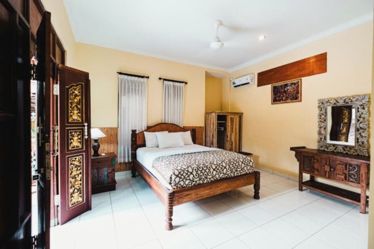 A bedroom with a wooden bed, a nightstand, a wardrobe, and a mirror on the wall.
