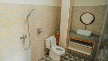 Baño con ducha, inodoro, lavabo y espejo.