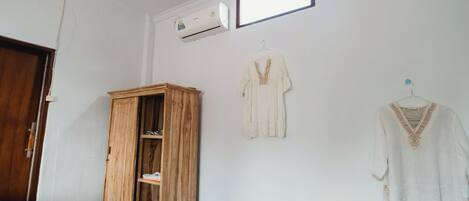 A room with a wooden wardrobe, a hanging light fixture, and a wall-mounted air conditioner.