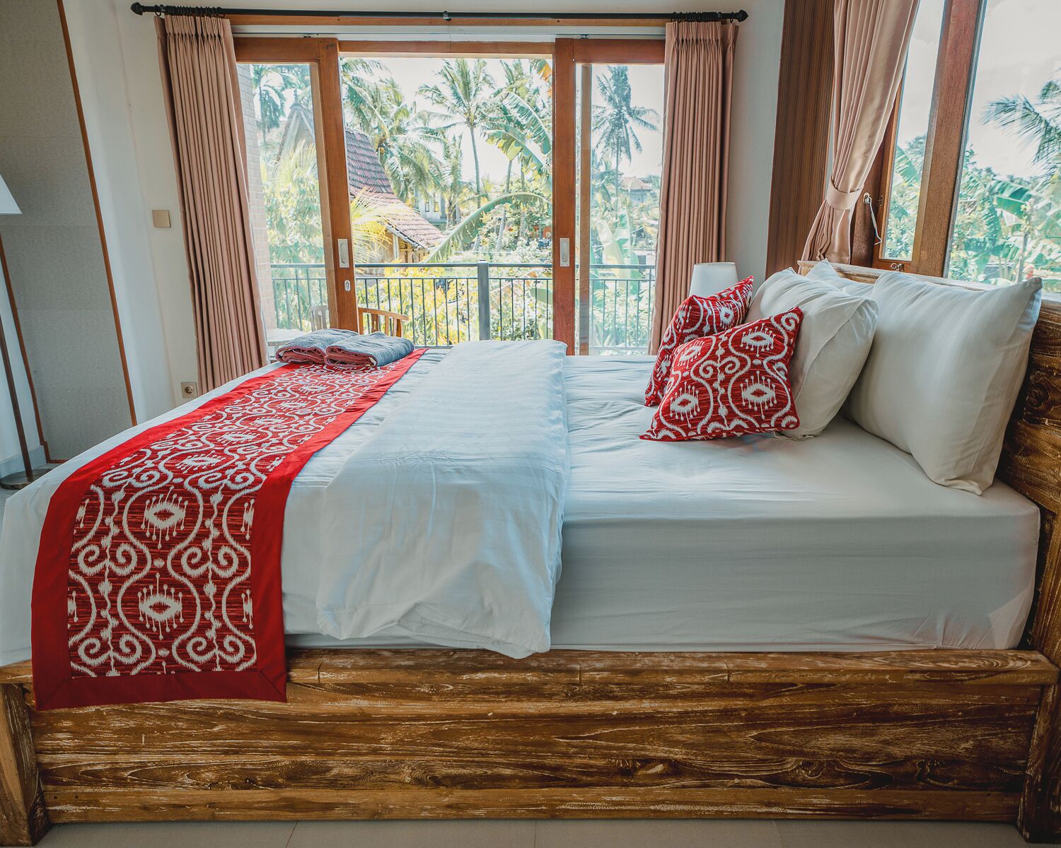 A double bed with a red and white patterned bedspread, white pillows, and a wooden headboard.