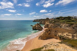 A coastal landscape with a sandy beach, rocky cliffs, and a clear blue sky. - Apartment Ludan with large balcony (Porches)