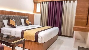 Una habitación de hotel moderna con una cama grande, cabecera de madera y aire acondicionado integrado.