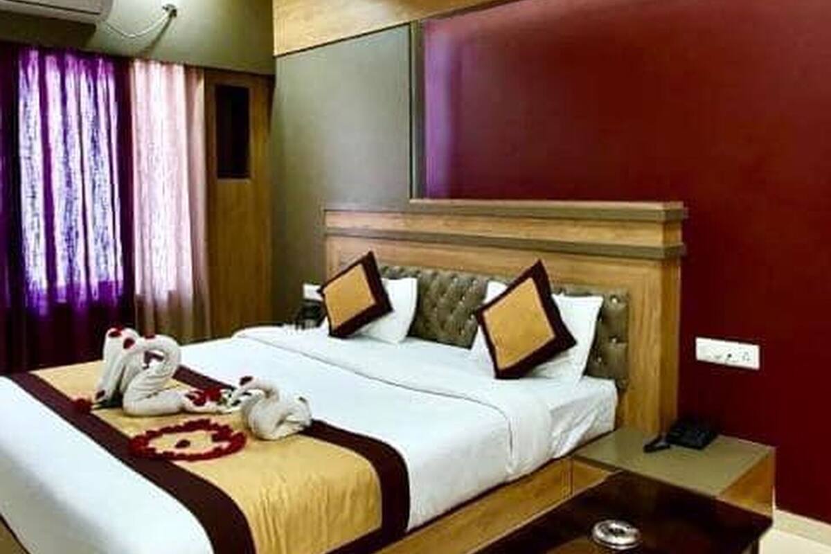 A hotel room with a bed, a bedside table, and a red accent wall.