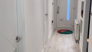 A hallway with white walls, a wooden floor, and a door at the end. - COP 26immaculate Newly Refurbished2 bed in Glasgow (Glasgow)