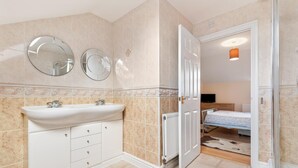 Casa de banho com lavatório, dois espelhos, radiador e zona de duche.