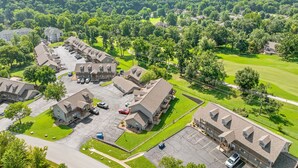 Vista aérea de una zona residencial con casas, un estacionamiento y un campo de golf al fondo.