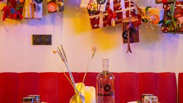 A restaurant with a red booth seating area, a candle centerpiece, and a bottle of L'O' Mulhouse on the table.