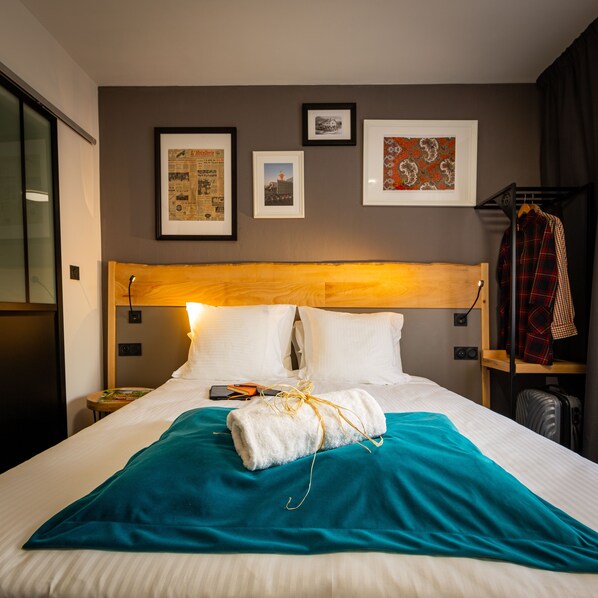 Ein Hotelzimmer mit einem ordentlich bezogenen Bett, einem hölzernen Kopfteil und einer Wand mit drei gerahmten Bildern.