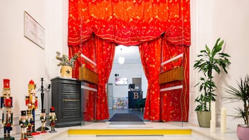 Una escalera conduce a una habitación con cortinas rojas, un escritorio y una planta.