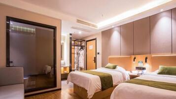 A hotel room with two beds, a seating area, and a mirror.