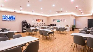 Uma sala de conferência com mesas, cadeiras, uma televisão e obras de arte nas paredes.