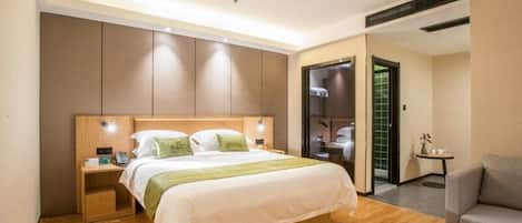 Quarto de hotel moderno com cama de madeira, mesa de cabeceira, mesinha e área de estar.
