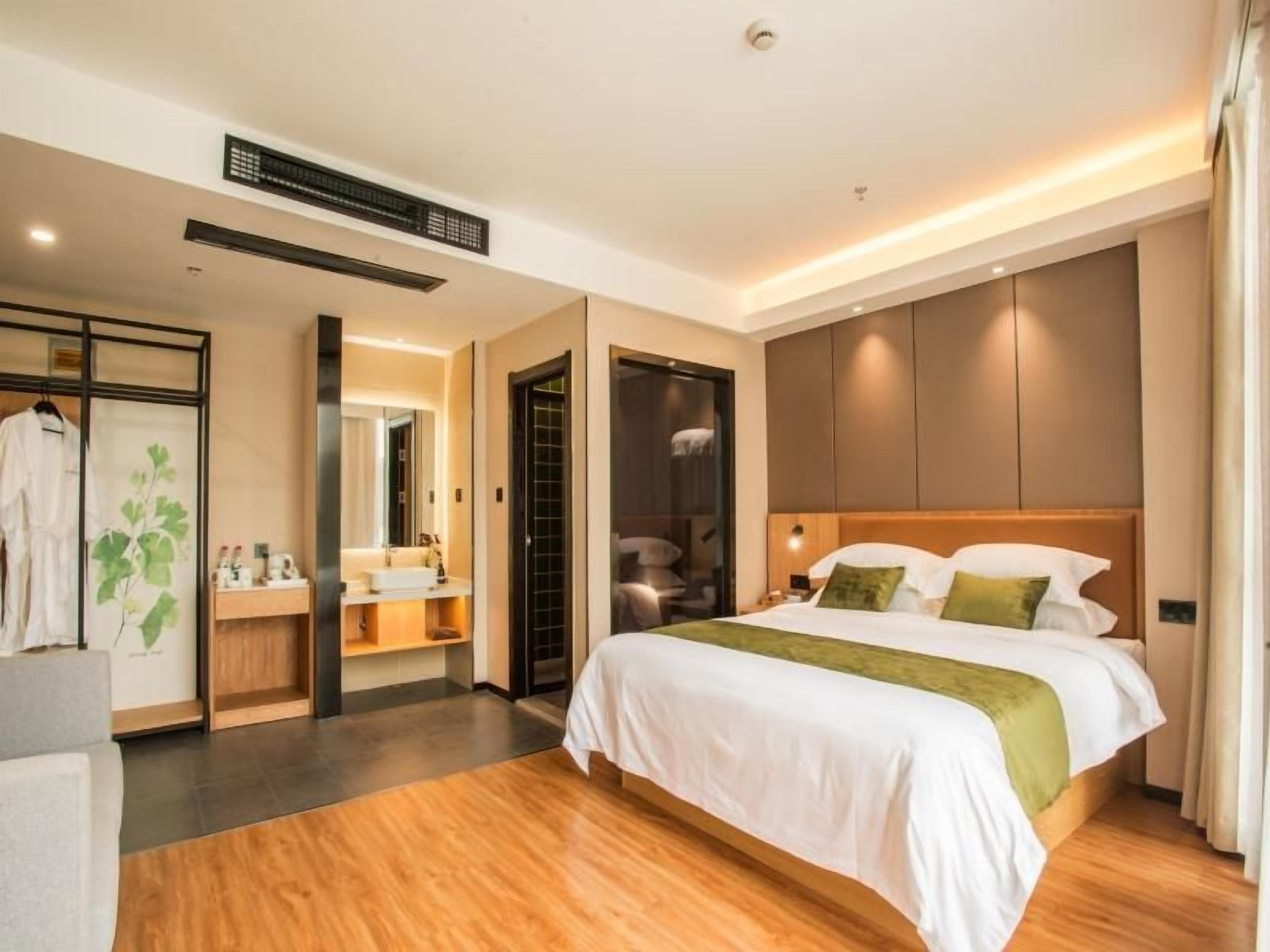 Ein modernes Hotelzimmer mit einem großen Bett, einem separaten Badezimmer und einem begehbaren Kleiderschrank.