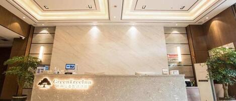 A reception desk with a sign reading "GreenTree Inn" and a digital display.