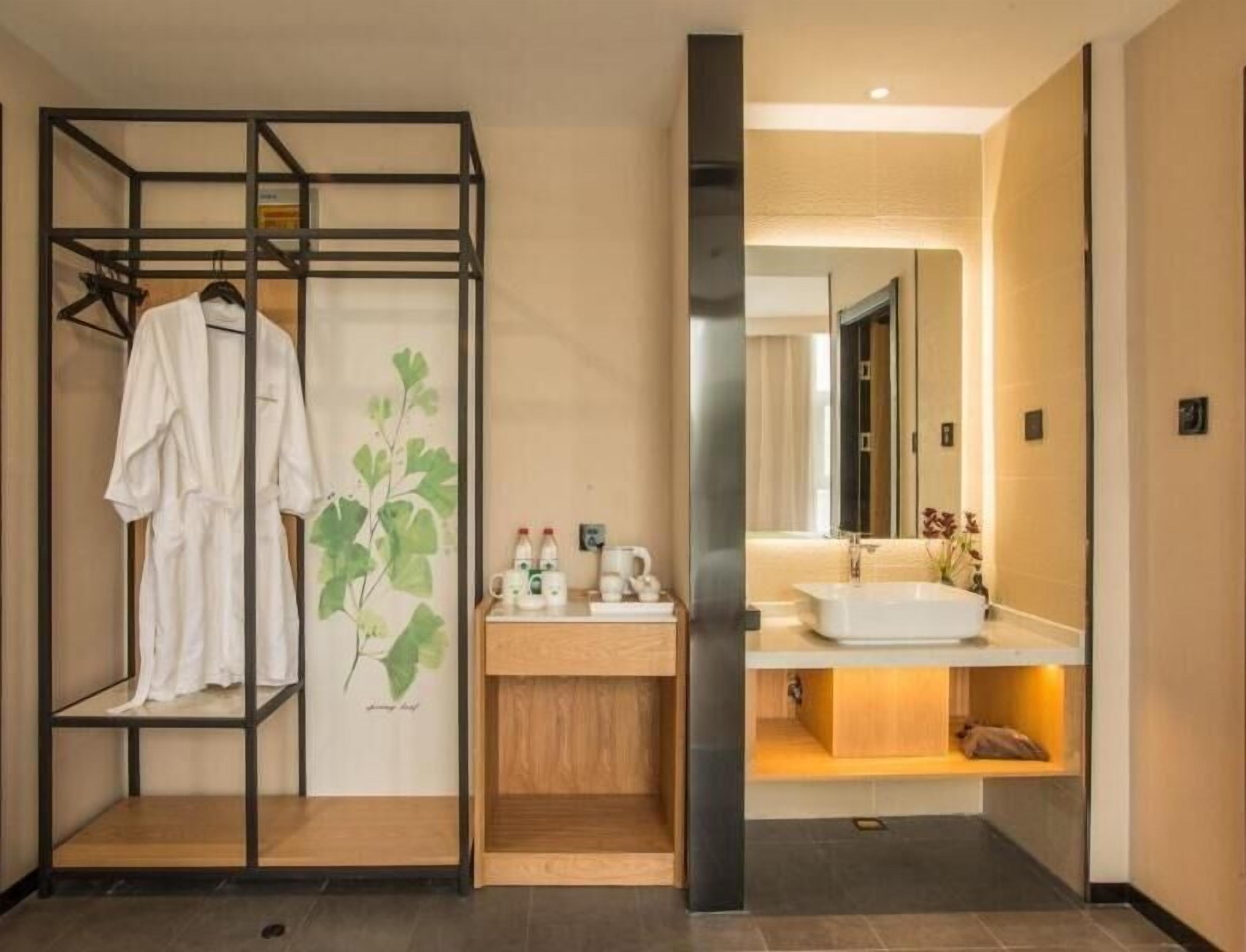 A modern bathroom with a wooden vanity, a large mirror, and a robe rack.