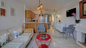 A modern living room with a sofa, a red coffee table, and a kitchen in the background. - Sea Views Beachfront Apt, Large Private Terrace (Benalmádena)