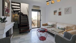 A modern living room with a staircase, a sofa set, a red coffee table, and a ceiling light fixture. - Sea Views Beachfront Apt, Large Private Terrace (Benalmádena)