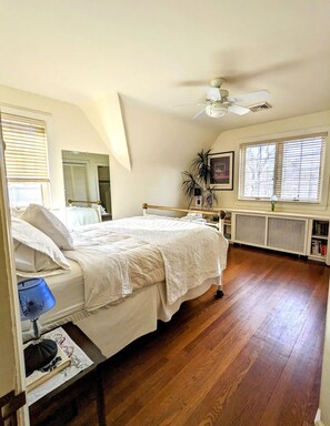 A bedroom with a bed, a ceiling fan, a radiator, and a window with blinds. - Historic Rustic Kingston Home. (KINGSTON)