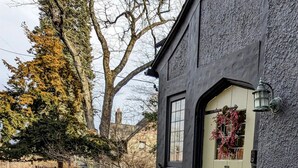 A stone staircase leading to a door with a wreath, a small potted plant, and a sign on the wall. - Historic Rustic Kingston Home. (KINGSTON)