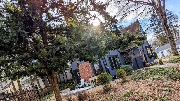 A modern building with a brick facade and large windows, surrounded by trees and a garden area. - Historic Rustic Kingston Home. (KINGSTON)
