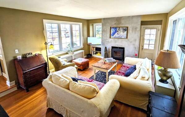 A living room with a fireplace, a sofa, a coffee table, and a television. - Historic Rustic Kingston Home. (KINGSTON)
