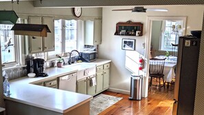 A kitchen with a large island, wooden flooring, and a dining area with a table and chairs. - Historic Rustic Kingston Home. (KINGSTON)
