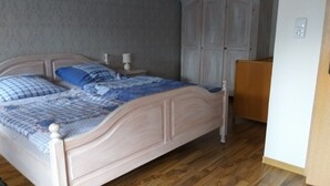 Une chambre à coucher avec un lit en bois, une table de chevet, une armoire et un bureau.