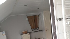 Une cuisine de taille réduite avec des meubles blancs, un petit plan de travail et un plancher en bois.