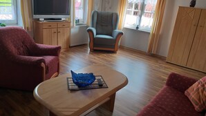 A living room with a television, two armchairs, a coffee table, and a wardrobe. - Vacation home, North Sea, Krummhörn, Upleward <br> (Krummhörn)
