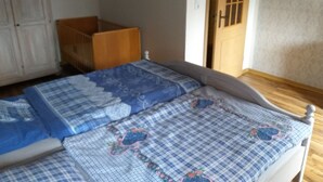 Une chambre à coucher avec un lit en bois, un berceau et une armoire.
