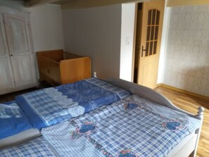 A bedroom with a wooden bed, a crib, and a wardrobe. - eeeeeereeee (Krummhörn)