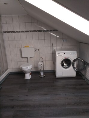 A compact laundry room with a toilet, washing machine, and a towel rack. - eeeeeereeee (Krummhörn)
