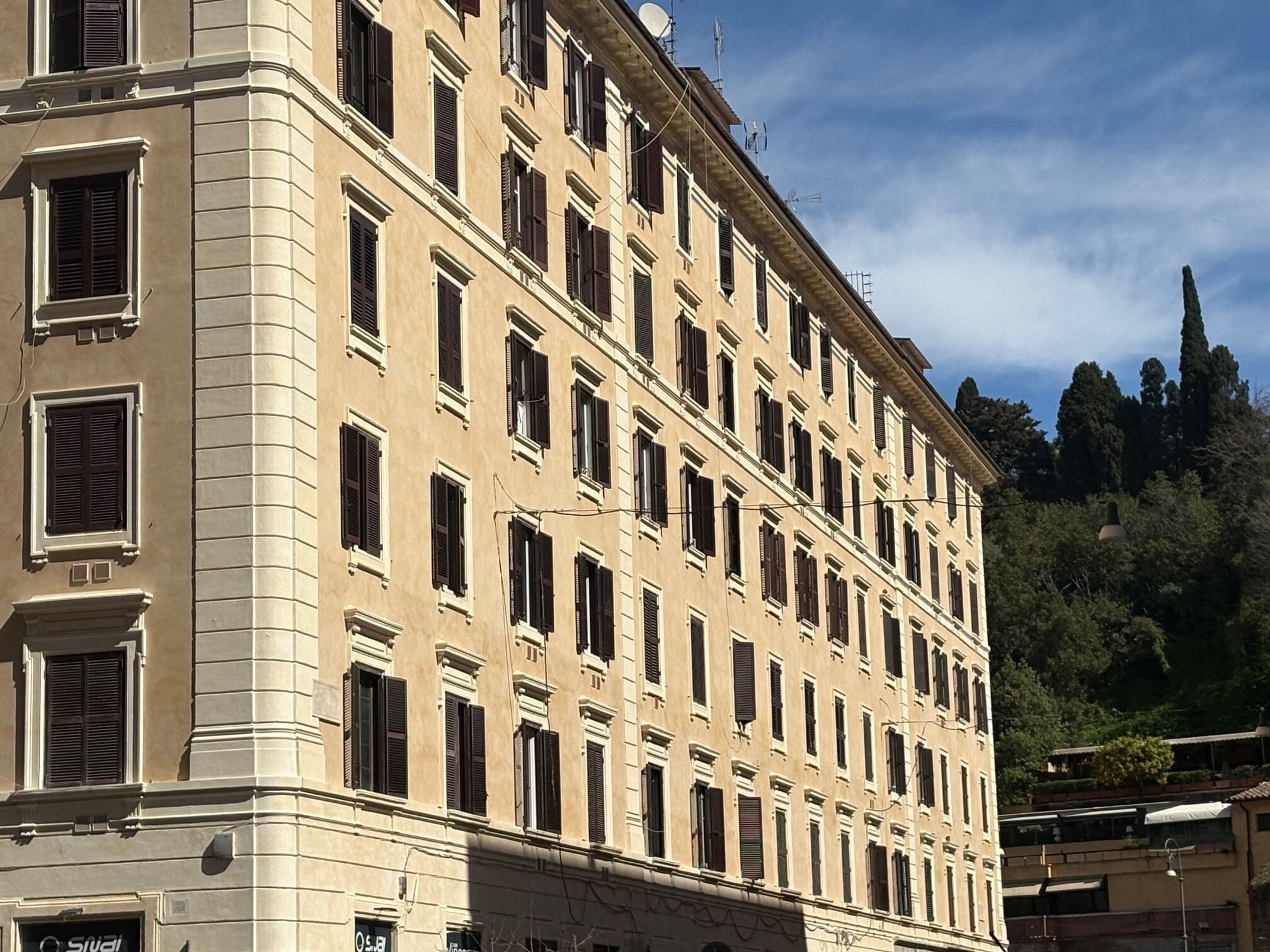 Ein mehrstöckiges Gebäude im klassischen Stil, mit einer symmetrischen Fassade und gleichmäßig verteilten Fenstern und Fensterläden.