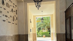 A hallway with a star-patterned floor, a hanging lantern, and a view of a garden with palm trees. - DELUXE SUITE extra king size bed, perfect location Rome center (rome)