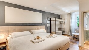 A modern hotel room with a large bed, a wardrobe, and a bathroom visible through an open door. - DELUXE SUITE extra king size bed, perfect location Rome center (rome)