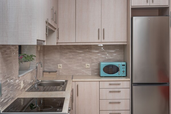 A modern kitchen with stainless steel appliances, light wood cabinets, and a marble backsplash. - Capostagno House Agapi - Stunning Views of Libyan Sea (Ano Rodakino)