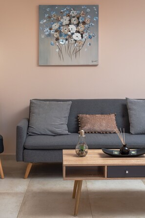 Una sala de estar moderna con un sofá gris, una mesa de centro de madera y un cuadro de flores en la pared.