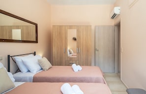 Una habitación de hotel con dos camas, un armario, un espejo y un equipo de aire acondicionado.
